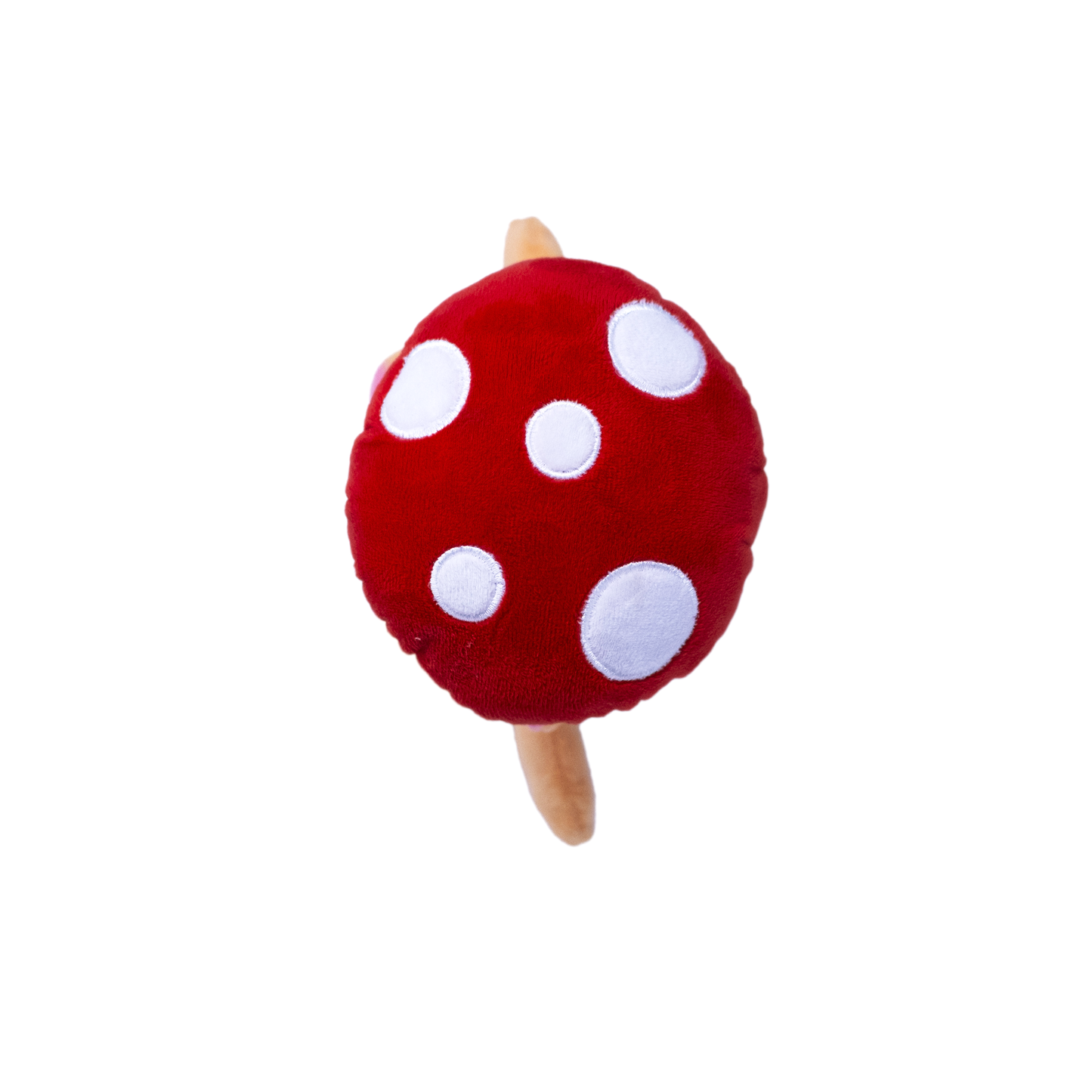 The top view of a plush red, white dog toy resembling a pig in a mushroom costume on a white background
